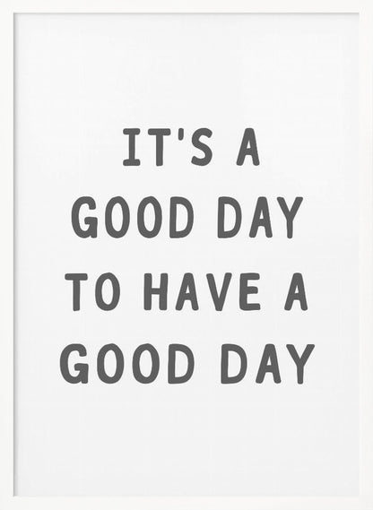 A framed black and white art print with the phrase 'IT'S A GOOD DAY TO HAVE A GOOD DAY' in a bold, dark gray, sans-serif font. Artwork
