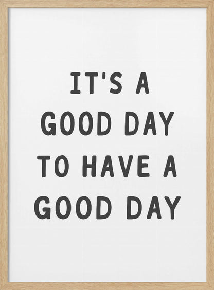 A framed black and white art print with the phrase 'IT'S A GOOD DAY TO HAVE A GOOD DAY' in a bold, dark gray, sans-serif font. Artwork