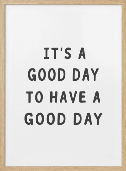 A framed black and white art print with the phrase 'IT'S A GOOD DAY TO HAVE A GOOD DAY' in a bold, dark gray, sans-serif font. Artwork
