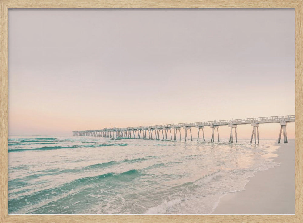 A tranquil beach scene with a long white pier extending into the turquoise ocean. The sky is a soft, pale pink, suggesting a serene sunrise or sunset, and gentle waves lap onto the sandy shore in the foreground. Poster