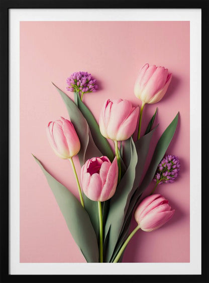 A top-down, artistic illustration of a bouquet of pink tulips and small purple flowers with long green leaves, arranged against a solid light pink background and displayed within a thin black frame. Wall Art