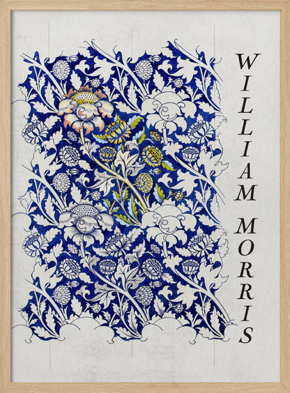 A vintage art print by William Morris featuring an intricate blue and white floral pattern on a light gray, textured background. The design swatch shows stylized flowers and acanthus leaves, with some central flowers highlighted in yellow and peach. The name 'WILLIAM MORRIS' is printed vertically in a black serif font along the right edge. The print is displayed in a thin black frame. Decor