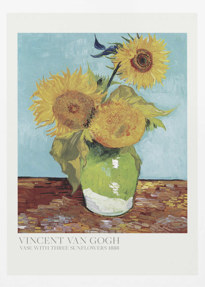 A framed art print of Vincent van Gogh's painting 'Vase with Three Sunflowers' from 1888. The artwork features three large, vibrant yellow sunflowers in a green vase set against a textured light blue background. The painting is in the post-impressionist style with thick, visible brushstrokes. The print has a white border with text at the bottom identifying the artist and title. Print
