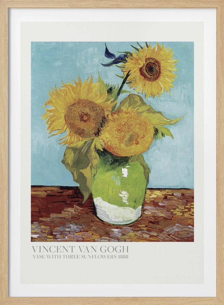 A framed art print of Vincent van Gogh's painting 'Vase with Three Sunflowers' from 1888. The artwork features three large, vibrant yellow sunflowers in a green vase set against a textured light blue background. The painting is in the post-impressionist style with thick, visible brushstrokes. The print has a white border with text at the bottom identifying the artist and title. Print