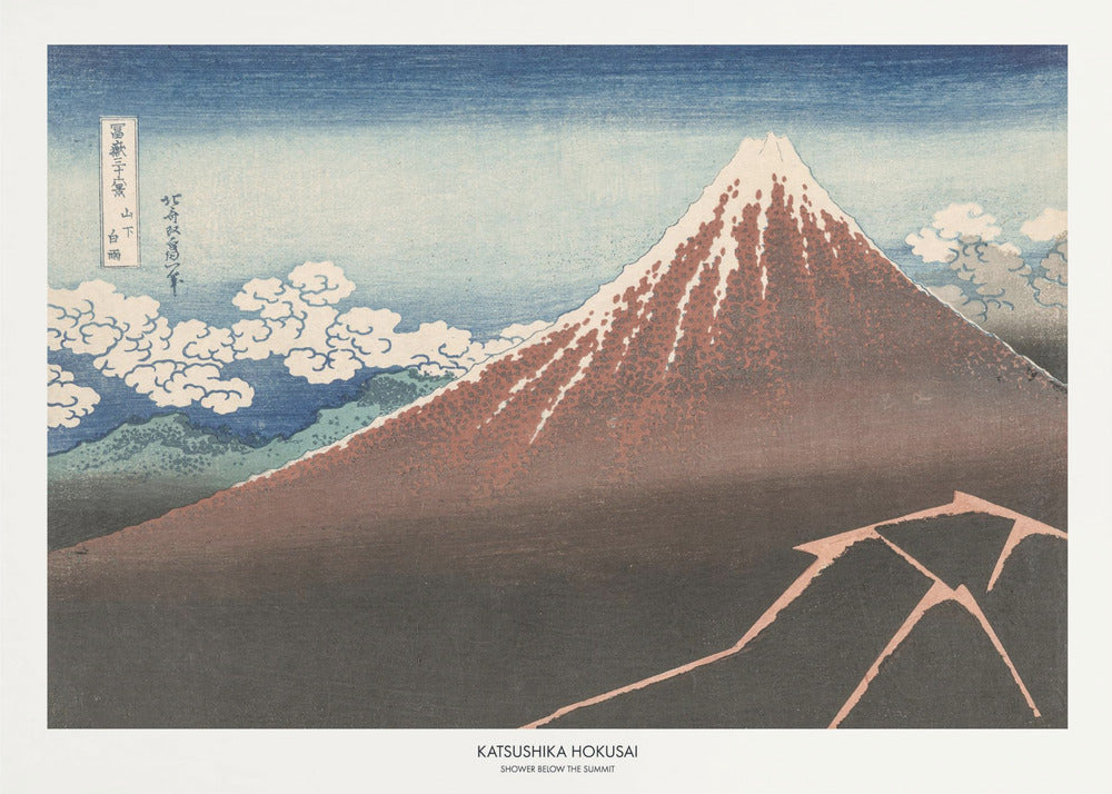 A framed Japanese woodblock print by Katsushika Hokusai titled 'Shower Below the Summit.' The print depicts a large, dark brown and reddish mountain, likely Mount Fuji, with a snow-capped peak. The sky above is a deep blue, and stylized white clouds are scattered around the mountain's slope. In the dark foreground, a jagged pink line represents a lightning strike. Artwork