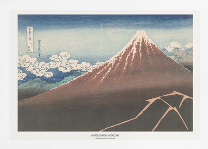 A framed Japanese woodblock print by Katsushika Hokusai titled 'Shower Below the Summit.' The print depicts a large, dark brown and reddish mountain, likely Mount Fuji, with a snow-capped peak. The sky above is a deep blue, and stylized white clouds are scattered around the mountain's slope. In the dark foreground, a jagged pink line represents a lightning strike. Artwork