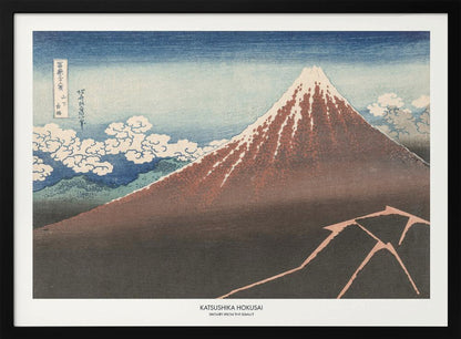 A framed Japanese woodblock print by Katsushika Hokusai titled 'Shower Below the Summit.' The print depicts a large, dark brown and reddish mountain, likely Mount Fuji, with a snow-capped peak. The sky above is a deep blue, and stylized white clouds are scattered around the mountain's slope. In the dark foreground, a jagged pink line represents a lightning strike. Artwork
