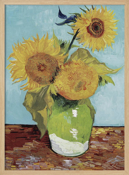 A framed reproduction of Vincent van Gogh's famous 'Sunflowers' painting, featuring three large yellow sunflowers in a green vase against a light blue background, painted in his iconic post-impressionist style with thick brushstrokes. Wall Art