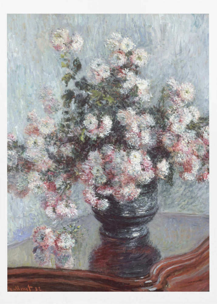 An impressionist painting by Claude Monet depicting a large bouquet of white and pink chrysanthemums in a dark, ornate vase. The vase sits on a reflective, reddish-brown wooden table, and the background is a textured light blue wall. The painting is framed in black. Artwork
