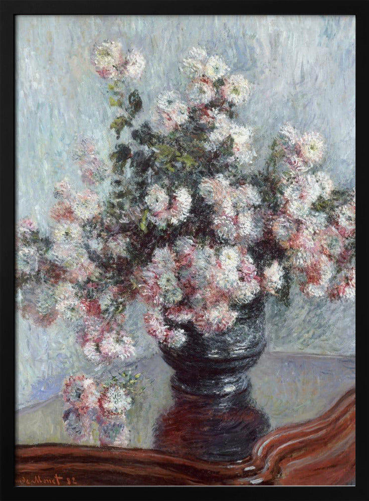 An impressionist painting by Claude Monet depicting a large bouquet of white and pink chrysanthemums in a dark, ornate vase. The vase sits on a reflective, reddish-brown wooden table, and the background is a textured light blue wall. The painting is framed in black. Artwork