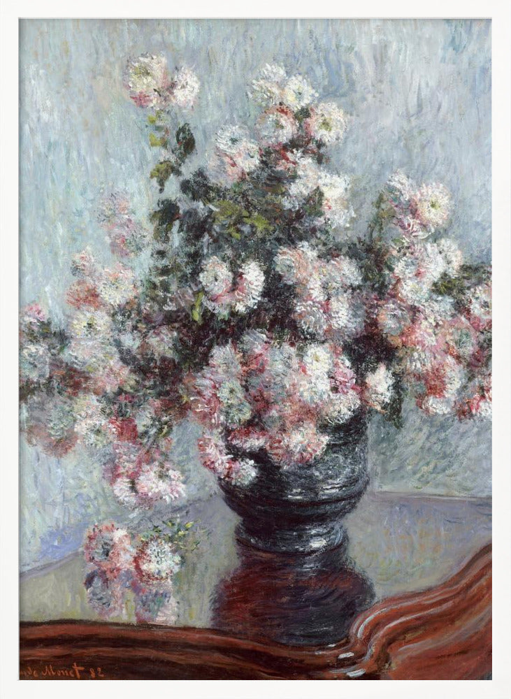 An impressionist painting by Claude Monet depicting a large bouquet of white and pink chrysanthemums in a dark, ornate vase. The vase sits on a reflective, reddish-brown wooden table, and the background is a textured light blue wall. The painting is framed in black. Artwork