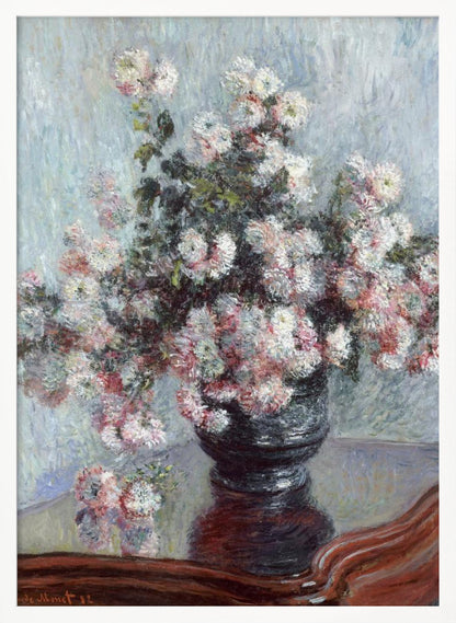 An impressionist painting by Claude Monet depicting a large bouquet of white and pink chrysanthemums in a dark, ornate vase. The vase sits on a reflective, reddish-brown wooden table, and the background is a textured light blue wall. The painting is framed in black. Artwork