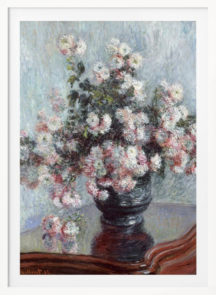 An impressionist painting by Claude Monet depicting a large bouquet of white and pink chrysanthemums in a dark, ornate vase. The vase sits on a reflective, reddish-brown wooden table, and the background is a textured light blue wall. The painting is framed in black. Artwork