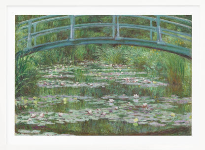 An Impressionist painting by Claude Monet depicting a green Japanese-style footbridge arching over a tranquil pond filled with blooming water lilies and lily pads, all rendered in soft, dappled brushstrokes and framed in a modern silver frame. Print