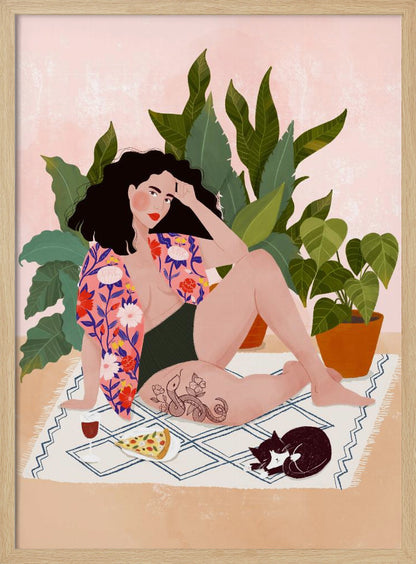 An illustration of a woman with dark curly hair relaxing on a patterned blanket indoors. She is wearing a green swimsuit and a pink floral shirt, with a prominent snake tattoo on her thigh. Next to her is a slice of pizza, a glass of red wine, and a sleeping black and white cat, all set against a backdrop of large green houseplants and a pink wall. Artwork
