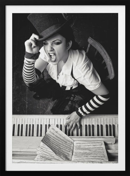 A dramatic black and white high-angle photograph of a woman in a top hat and striped arm warmers, shouting or singing passionately while seated at a piano with sheet music. Print