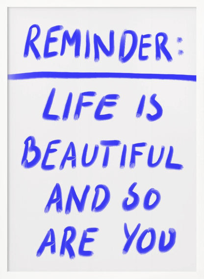 A framed poster featuring a positive affirmation handwritten in a blue, brush-stroke style font on a white background. The text reads 'REMINDER: LIFE IS BEAUTIFUL AND SO ARE YOU', with a blue line separating 'REMINDER:' from the rest of the quote. Print