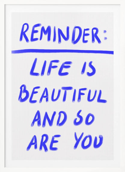 A framed poster featuring a positive affirmation handwritten in a blue, brush-stroke style font on a white background. The text reads 'REMINDER: LIFE IS BEAUTIFUL AND SO ARE YOU', with a blue line separating 'REMINDER:' from the rest of the quote. Print