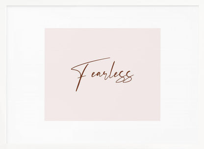 A framed artwork featuring the word 'Fearless' in a flowing brown script font on a pale pink background. The piece is surrounded by a white mat and a textured silver frame. Wall Art