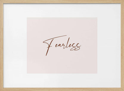 A framed artwork featuring the word 'Fearless' in a flowing brown script font on a pale pink background. The piece is surrounded by a white mat and a textured silver frame. Wall Art