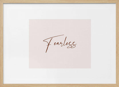 A framed artwork featuring the word 'Fearless' in a flowing brown script font on a pale pink background. The piece is surrounded by a white mat and a textured silver frame. Wall Art