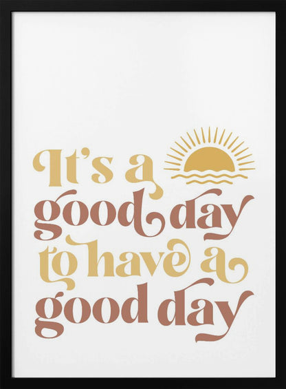 A framed art print with a white background featuring the quote 'It's a good day to have a good day' in a retro, curvy font. The text color alternates between terracotta brown and mustard yellow. Above the text is a small yellow icon of a sun rising over waves. Wall Art