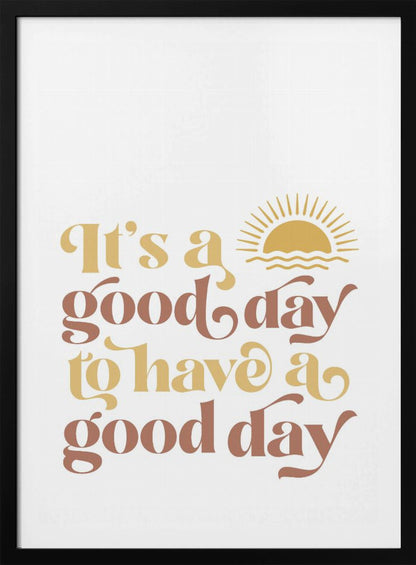A framed art print with a white background featuring the quote 'It's a good day to have a good day' in a retro, curvy font. The text color alternates between terracotta brown and mustard yellow. Above the text is a small yellow icon of a sun rising over waves. Wall Art