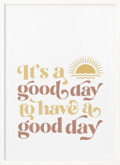 A framed art print with a white background featuring the quote 'It's a good day to have a good day' in a retro, curvy font. The text color alternates between terracotta brown and mustard yellow. Above the text is a small yellow icon of a sun rising over waves. Wall Art