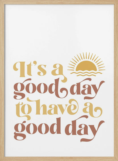 A framed art print with a white background featuring the quote 'It's a good day to have a good day' in a retro, curvy font. The text color alternates between terracotta brown and mustard yellow. Above the text is a small yellow icon of a sun rising over waves. Wall Art