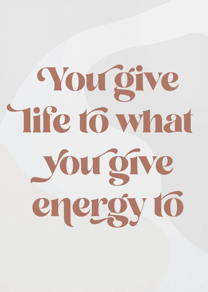 A framed motivational poster featuring the quote 'You give life to what you give energy to'. The text is printed in a dusty rose color using a stylish, retro serif font on a light gray background with subtle wavy shapes. Poster