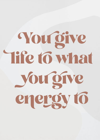 A framed motivational poster featuring the quote 'You give life to what you give energy to'. The text is printed in a dusty rose color using a stylish, retro serif font on a light gray background with subtle wavy shapes. Poster