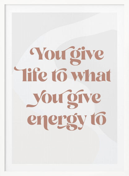 A framed motivational poster featuring the quote 'You give life to what you give energy to'. The text is printed in a dusty rose color using a stylish, retro serif font on a light gray background with subtle wavy shapes. Poster