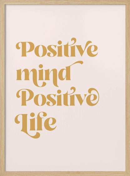 A framed art print featuring the motivational quote 'Positive mind Positive life' in a gold, retro-style font against a light pink background. The text is centered and arranged vertically. Artwork