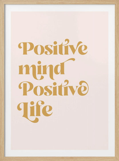 A framed art print featuring the motivational quote 'Positive mind Positive life' in a gold, retro-style font against a light pink background. The text is centered and arranged vertically. Artwork