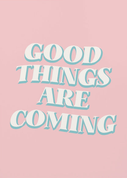 A framed poster with a light pink background featuring the motivational phrase 'GOOD THINGS ARE COMING'. The text is in a white, retro-style serif font with a light blue drop shadow, giving it a three-dimensional effect. Poster