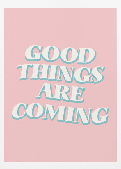 A framed poster with a light pink background featuring the motivational phrase 'GOOD THINGS ARE COMING'. The text is in a white, retro-style serif font with a light blue drop shadow, giving it a three-dimensional effect. Poster