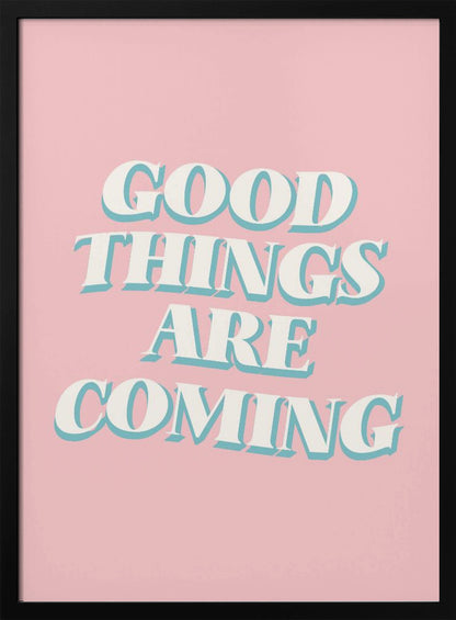 A framed poster with a light pink background featuring the motivational phrase 'GOOD THINGS ARE COMING'. The text is in a white, retro-style serif font with a light blue drop shadow, giving it a three-dimensional effect. Poster