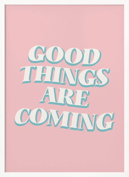 A framed poster with a light pink background featuring the motivational phrase 'GOOD THINGS ARE COMING'. The text is in a white, retro-style serif font with a light blue drop shadow, giving it a three-dimensional effect. Poster