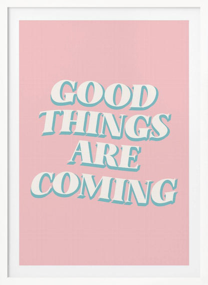 A framed poster with a light pink background featuring the motivational phrase 'GOOD THINGS ARE COMING'. The text is in a white, retro-style serif font with a light blue drop shadow, giving it a three-dimensional effect. Poster