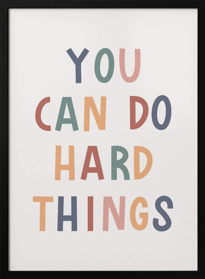 A framed poster featuring the inspirational quote 'YOU CAN DO HARD THINGS'. The text is in a simple, uppercase, sans-serif font with each letter in a different muted color, including shades of blue, green, pink, and orange, on a clean white background. Print