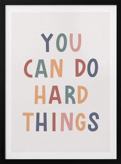 A framed poster featuring the inspirational quote 'YOU CAN DO HARD THINGS'. The text is in a simple, uppercase, sans-serif font with each letter in a different muted color, including shades of blue, green, pink, and orange, on a clean white background. Print