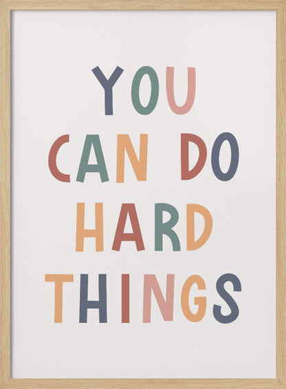 A framed poster featuring the inspirational quote 'YOU CAN DO HARD THINGS'. The text is in a simple, uppercase, sans-serif font with each letter in a different muted color, including shades of blue, green, pink, and orange, on a clean white background. Print