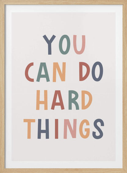 A framed poster featuring the inspirational quote 'YOU CAN DO HARD THINGS'. The text is in a simple, uppercase, sans-serif font with each letter in a different muted color, including shades of blue, green, pink, and orange, on a clean white background. Print