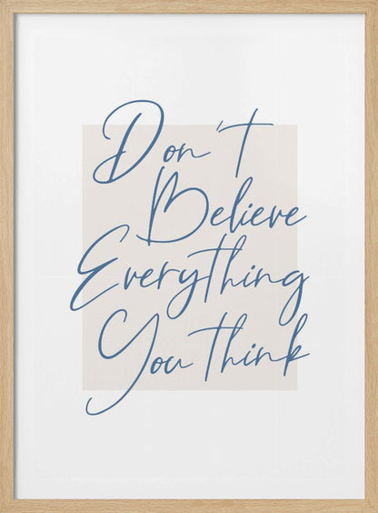 A minimalist art print in a black frame with the quote 'Don't Believe Everything You Think' written in blue cursive script. The text is set against a light beige rectangular background on a white canvas. Wall Art