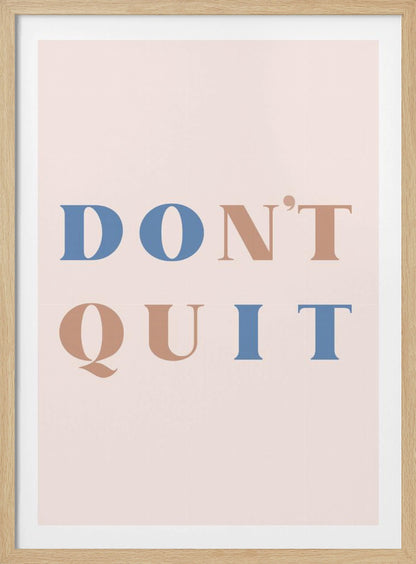 A minimalist motivational art print with a pale pink background and a thin black frame. The text reads 'DON'T QUIT' in a large serif font, with the words 'DO' and 'IT' highlighted in blue and the words 'N'T' and 'QU' in a muted terracotta color, creating a hidden 'DO IT' message. Decor