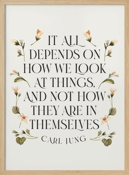 A framed art print featuring an inspirational quote by Carl Jung. The text reads 'It all depends on how we look at things, and not how they are in themselves' in a black serif font against an off-white background. The quote is encircled by a delicate wreath of watercolor botanicals with green leaves and pale orange flowers. Poster