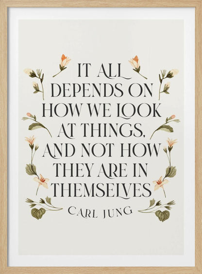 A framed art print featuring an inspirational quote by Carl Jung. The text reads 'It all depends on how we look at things, and not how they are in themselves' in a black serif font against an off-white background. The quote is encircled by a delicate wreath of watercolor botanicals with green leaves and pale orange flowers. Poster