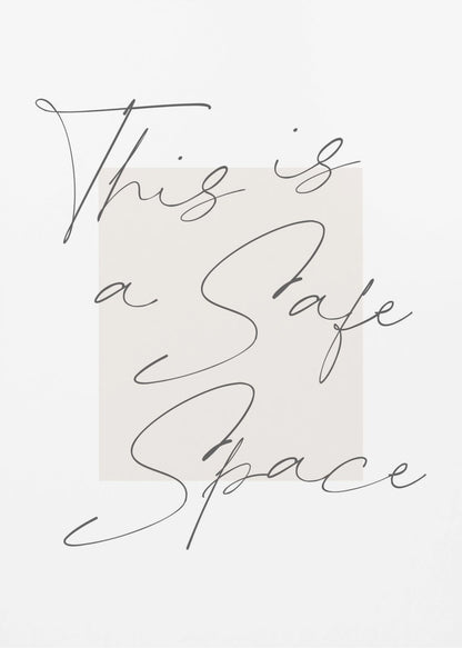 A minimalist art print in a black frame with the words 'This is a Safe Space' written in a flowing black cursive script over a pale beige rectangle on a white background. Artwork