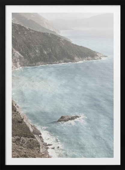 A high-angle photograph of a rugged, green coastline meeting a misty, light-blue ocean. The hazy atmosphere softens the view of the distant mountains and the waves crashing against the rocky shores. Poster