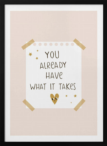 A motivational poster in a black frame with a pale pink background. A white piece of notebook paper is taped to the center with the handwritten text 'YOU ALREADY HAVE WHAT IT TAKES' in brown. It's decorated with small gold stars and a cute, smiling gold heart. Decor